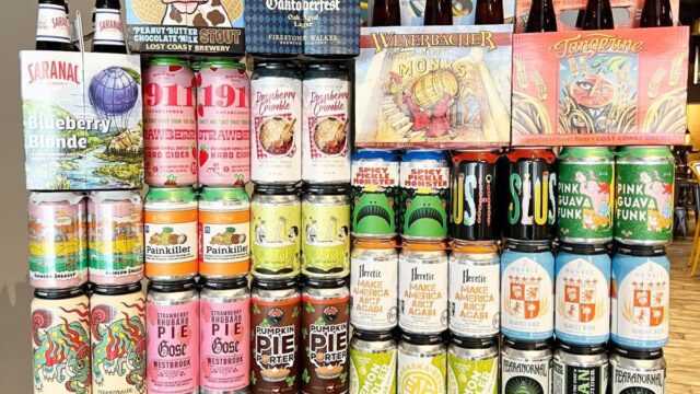 Cans and bottles of beer stacked in a colorful display on a blue table