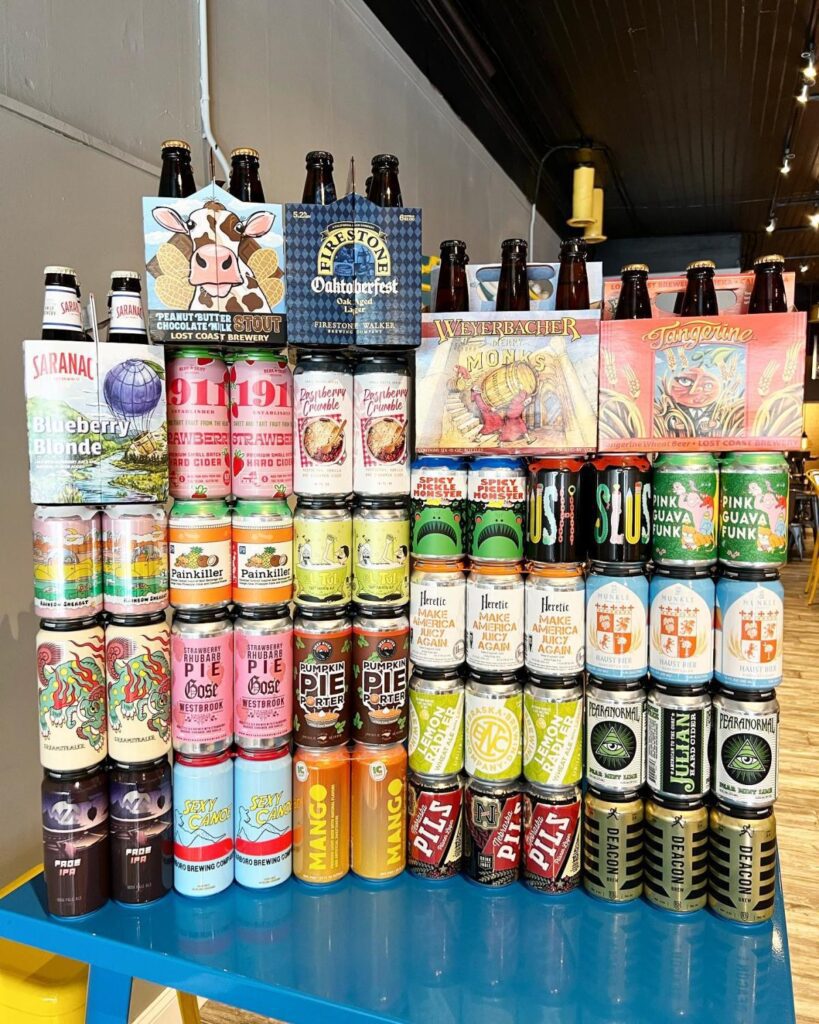 Cans and bottles of beer stacked in a colorful display on a blue table