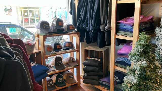 Clothing hung on hangers and folded on wooden shelves in a clothing store