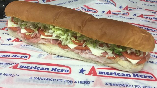 A sub sandwich with lettuce, tomato, cheese, and meat on an American Hero wrapper