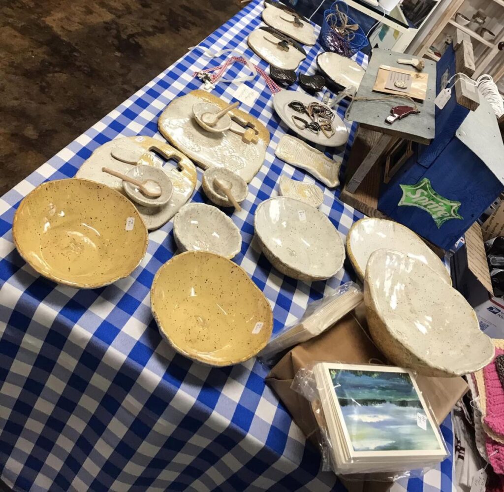 Pottery dishes sit on display on a table covered with a blue checked tablecloth at an artisan emporium