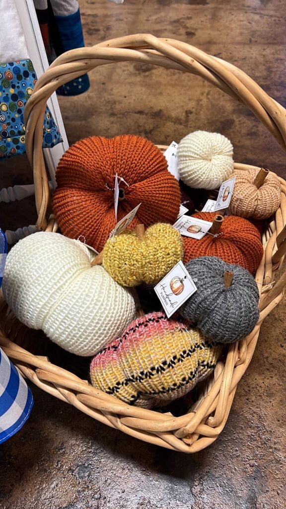 Knitted pumpkins in fall colors sit in a wooden basket