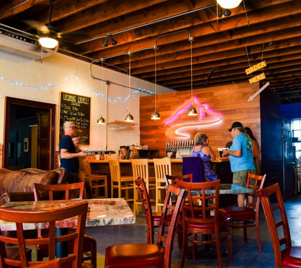 People socializing at a bar surrounded by tables and chairs