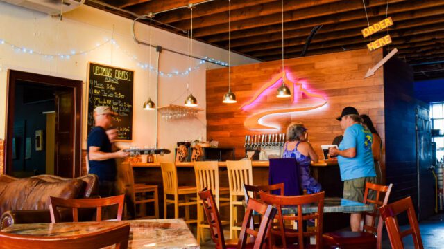 People socializing at a bar surrounded by tables and chairs