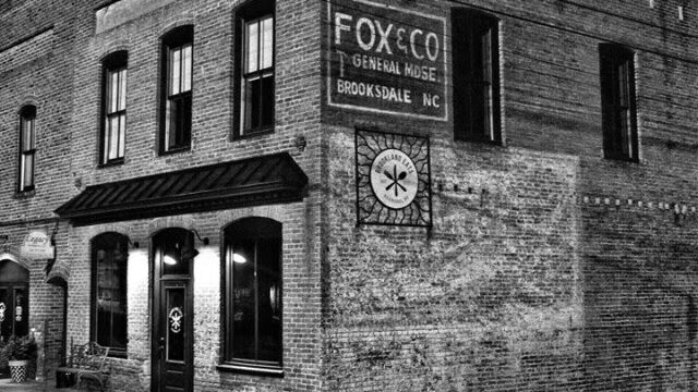 A black and white photo of a Fox & Co sign on the exterior of a brick building