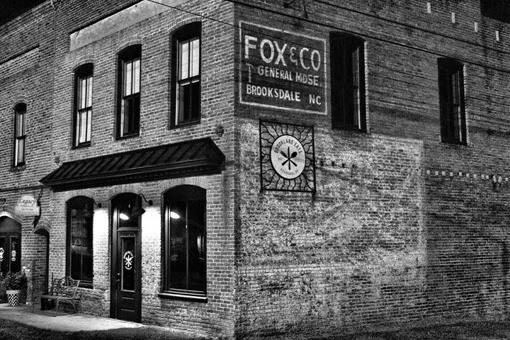 A black and white photo of a Fox & Co sign on the exterior of a brick building