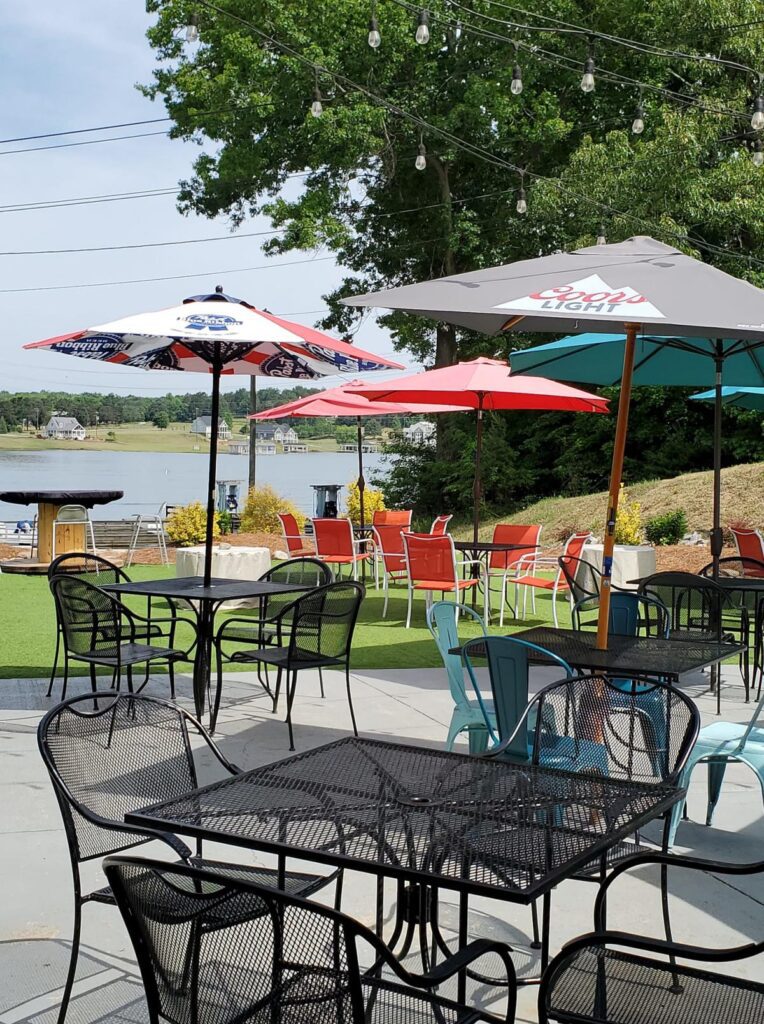 An outdoor patio at a restaurant with black metal tables and chairs with colorful shade umbrellas