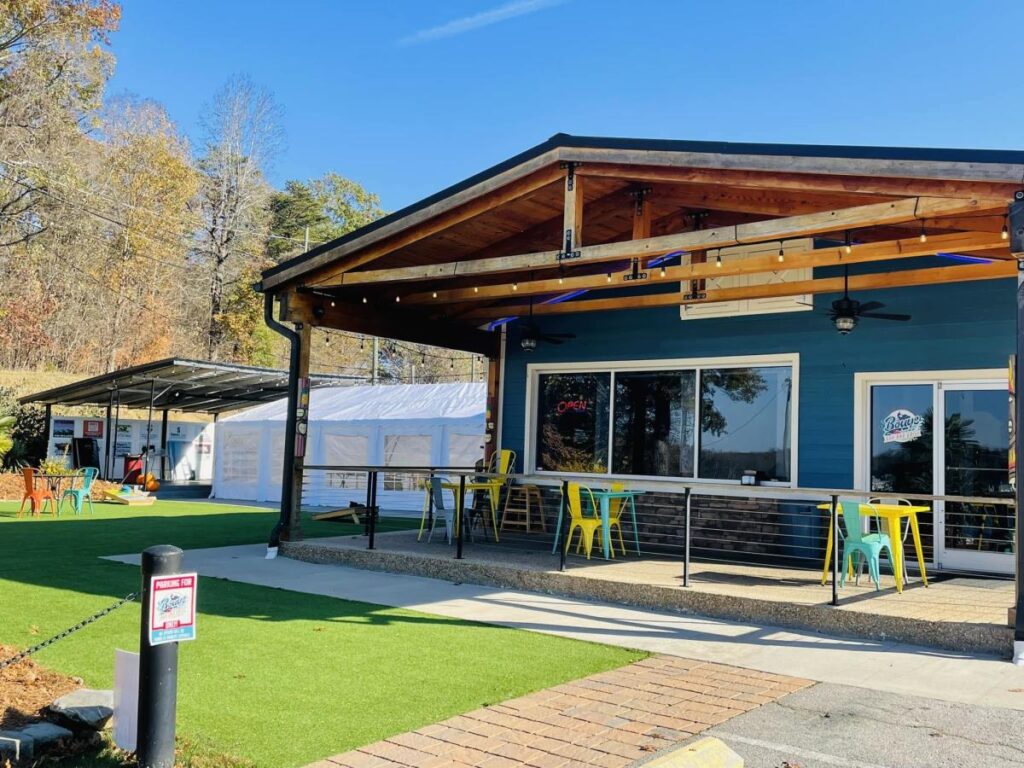 An outdoor space at a restaurant with tables and chairs on a patio and a green space