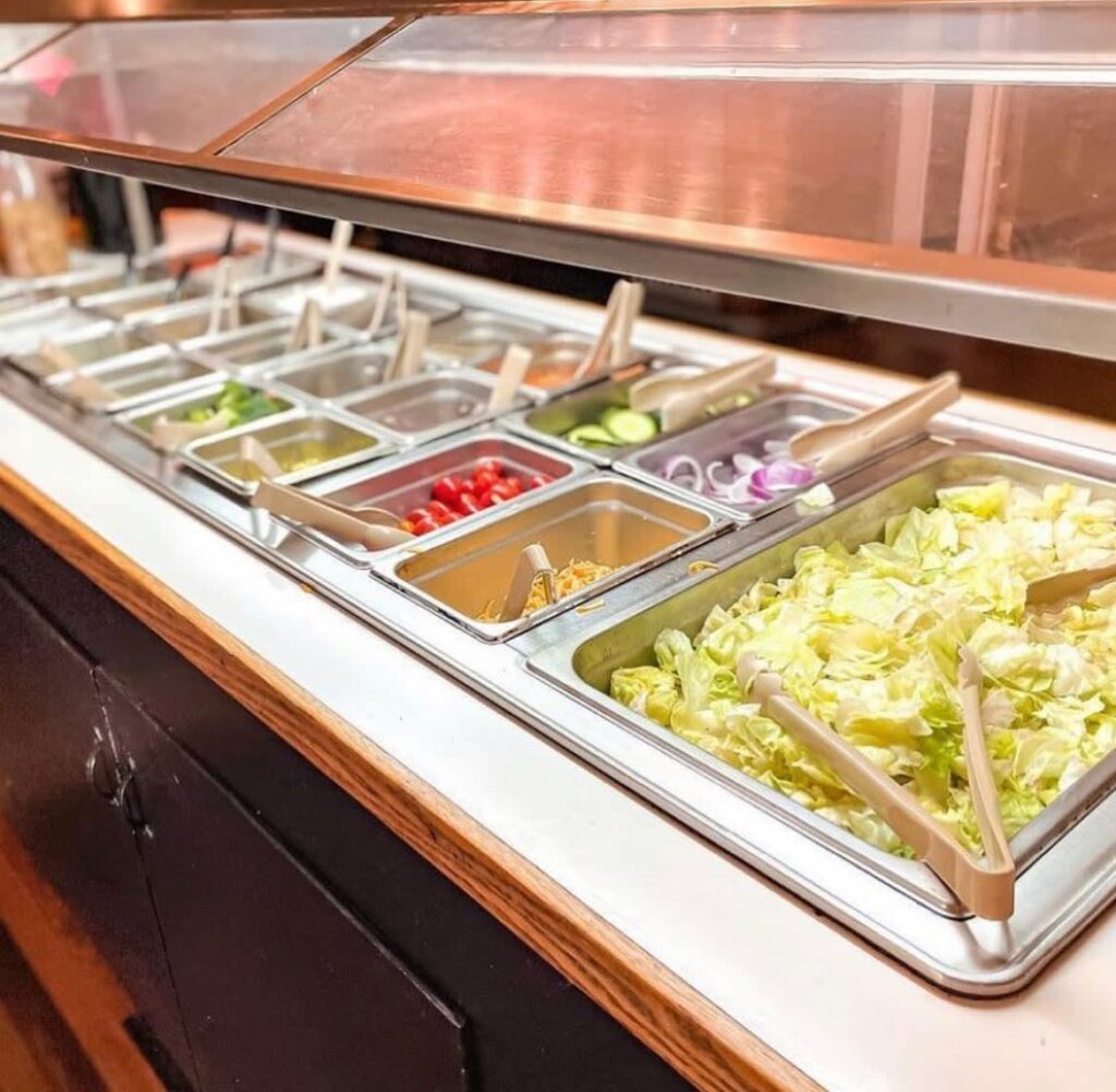 A buffet filled with food items and serving tongs