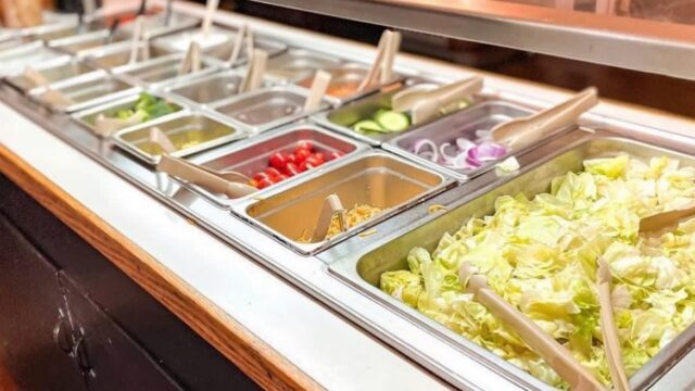 A buffet filled with food items and serving tongs