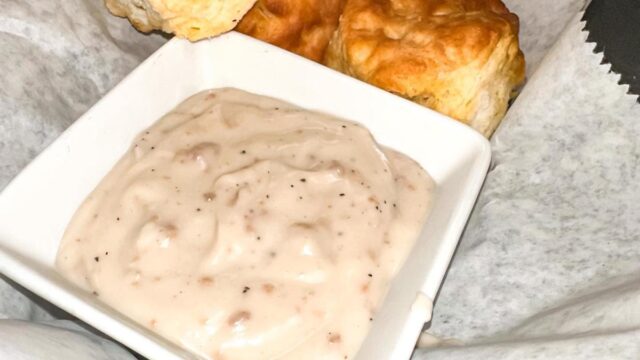 Four biscuits and a side of gravy served in a basket