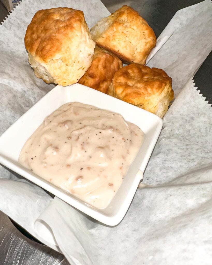 Four biscuits and a side of gravy served in a basket