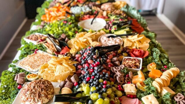 A catering table covered with grapes, sliced cheese and crackers