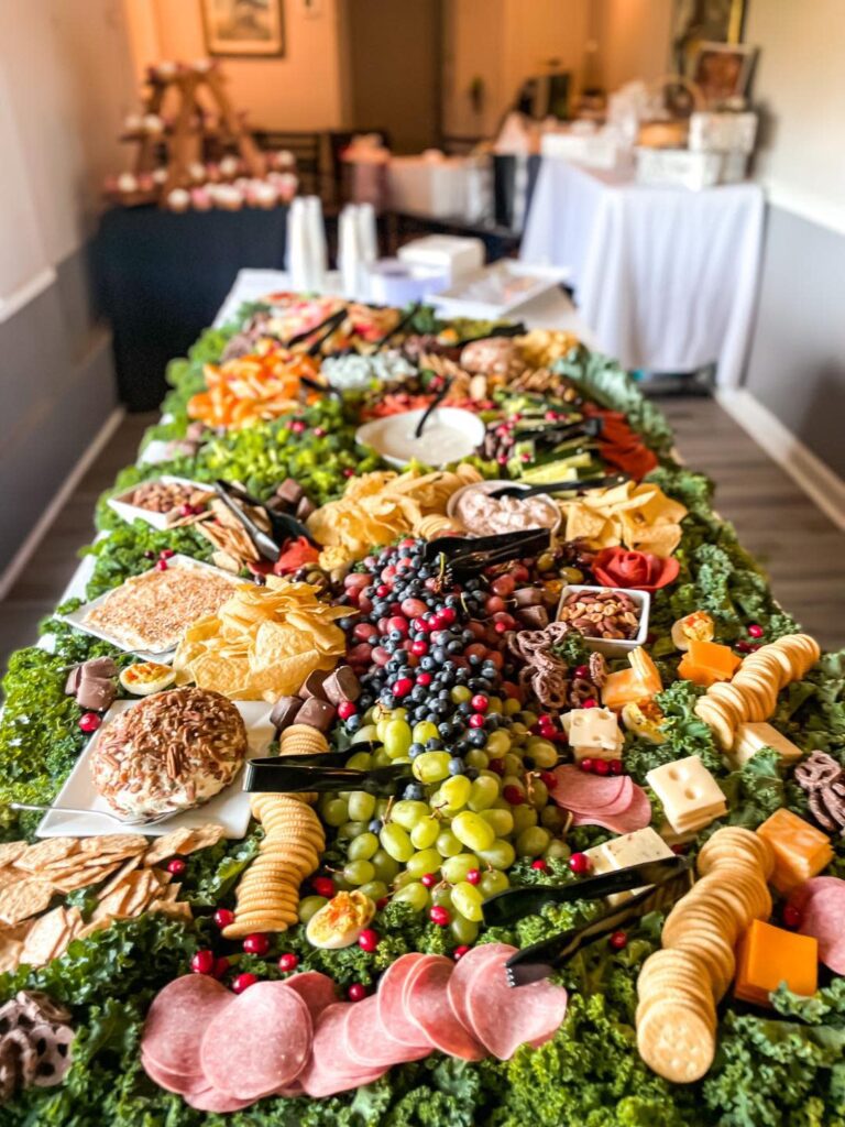 A catering table covered with grapes, sliced cheese and crackers