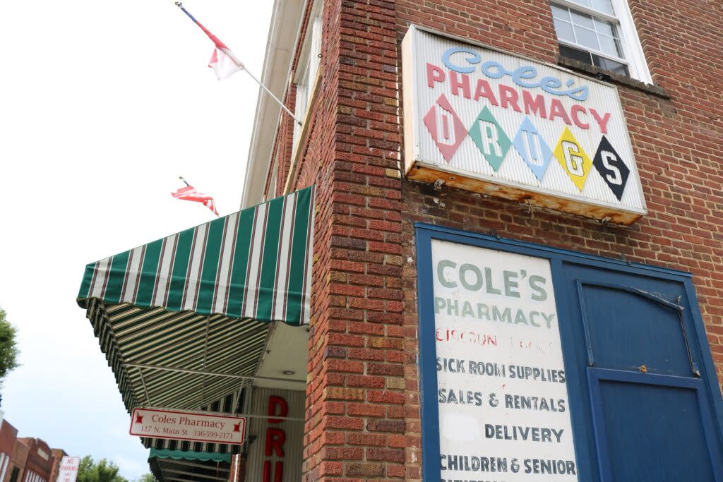 A sign on a building reading Cole's Pharmacy Drugs