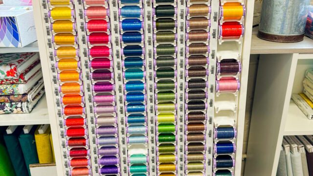 A craft store display with dozens of spools of thread in different colors