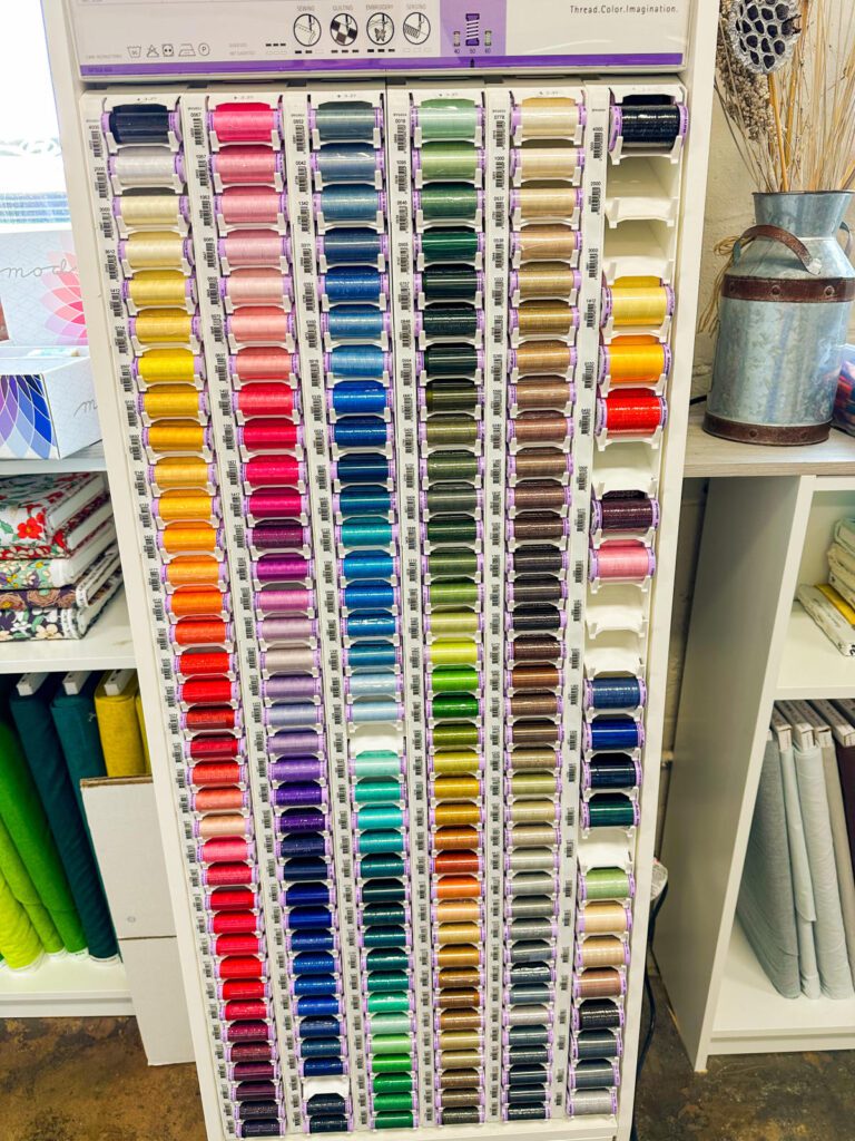 A craft store display with dozens of spools of thread in different colors