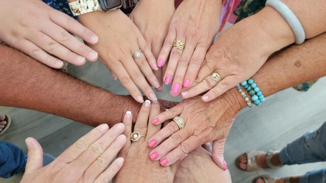 Ten people place their hands together in the center of a circle