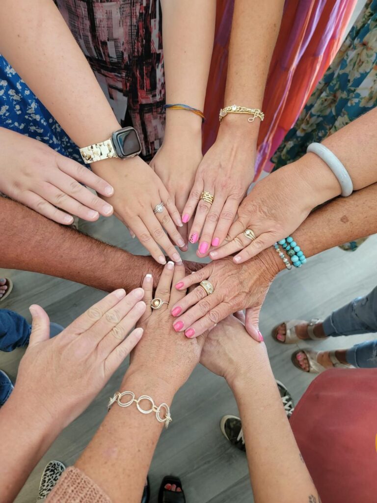 Ten people place their hands together in the center of a circle