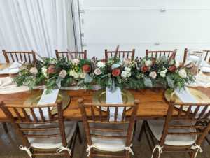 A wooden table is decorated with a long flower arrangement