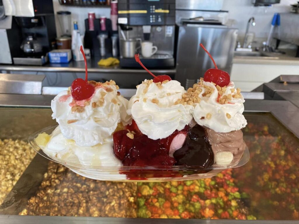 A banana split topped with whipped cream and maraschino cherries on top of a restaurant counter
