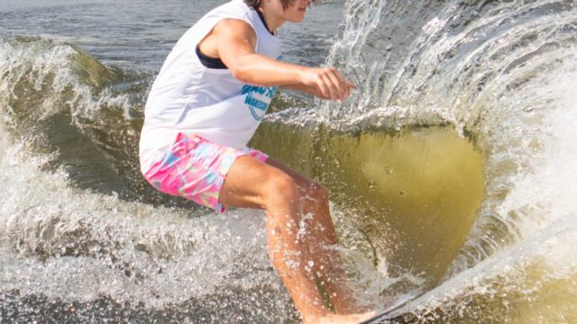 A wakeboarder on a lake with a large wake splashing around