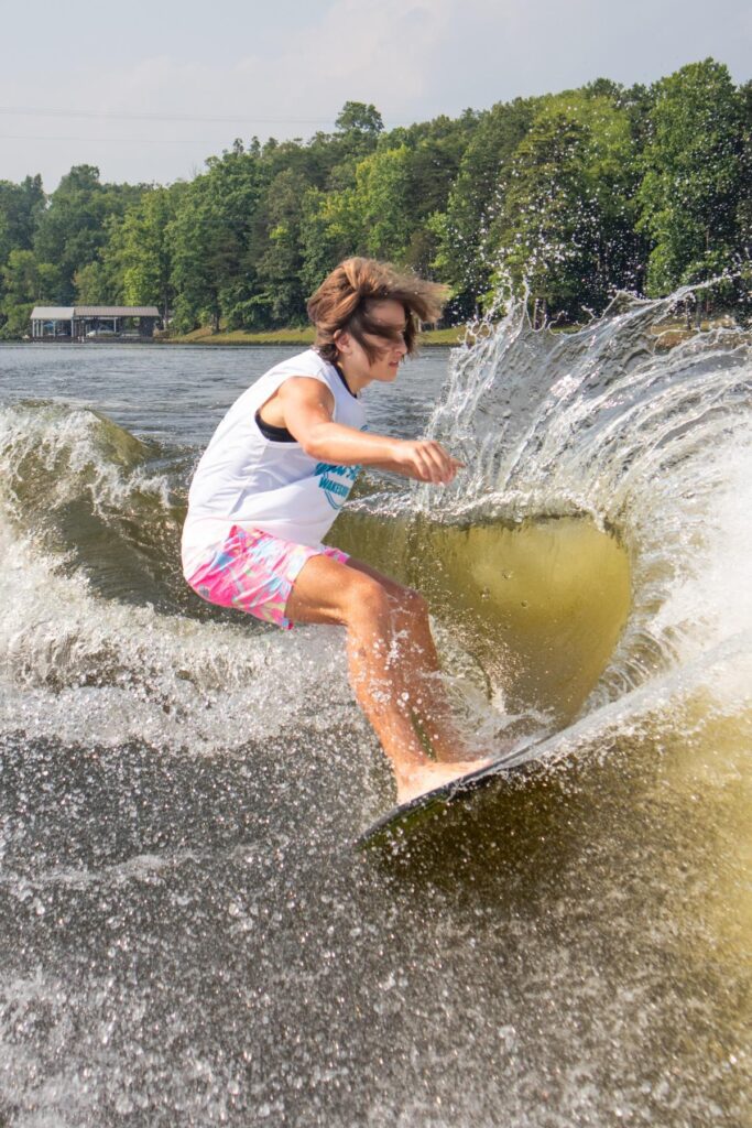 A wakeboarder on a lake with a large wake splashing around