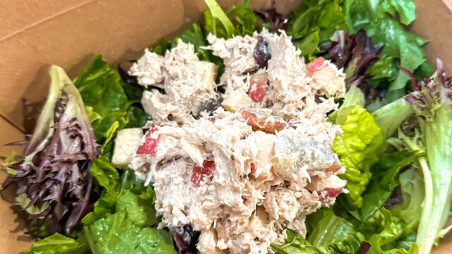 A brown cardboard to-go container filled with tuna salad on a bed of lettuce