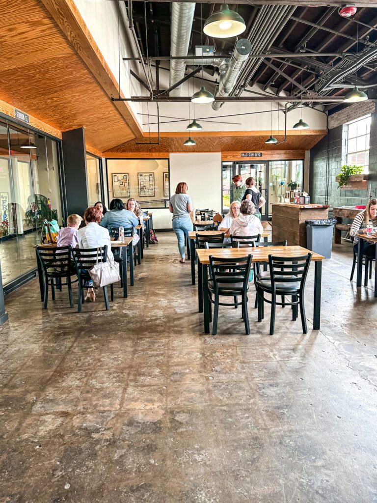 Diners sit in a restaurant with wooden tables and black chairs