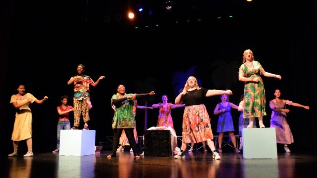 Performers sing and dance on stage