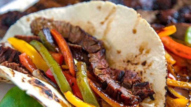 A fajita with meat and vegetables on a white plate