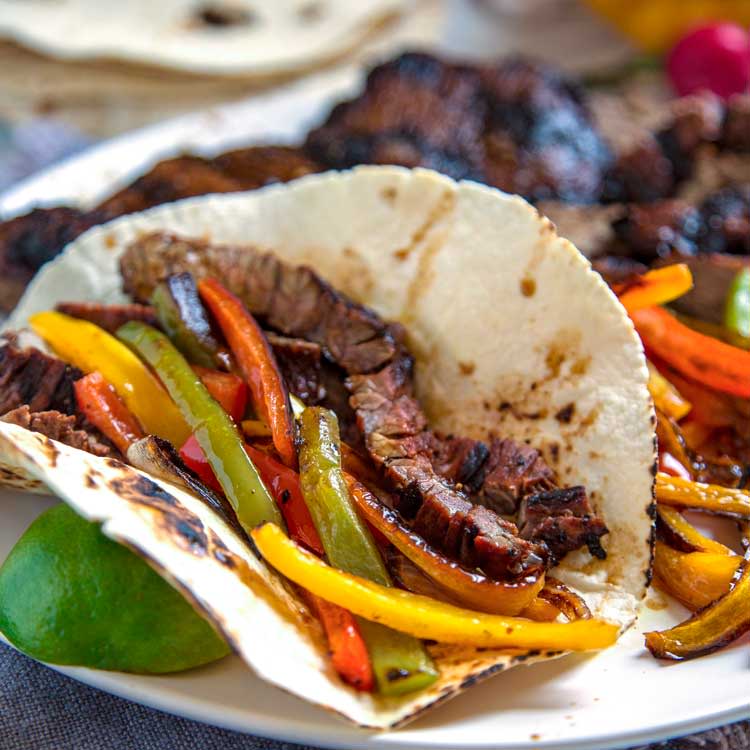 A fajita with meat and vegetables on a white plate