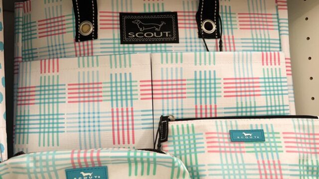 A selection of handbags and toiletry bags with a geometric print with pink, green, and blue lines