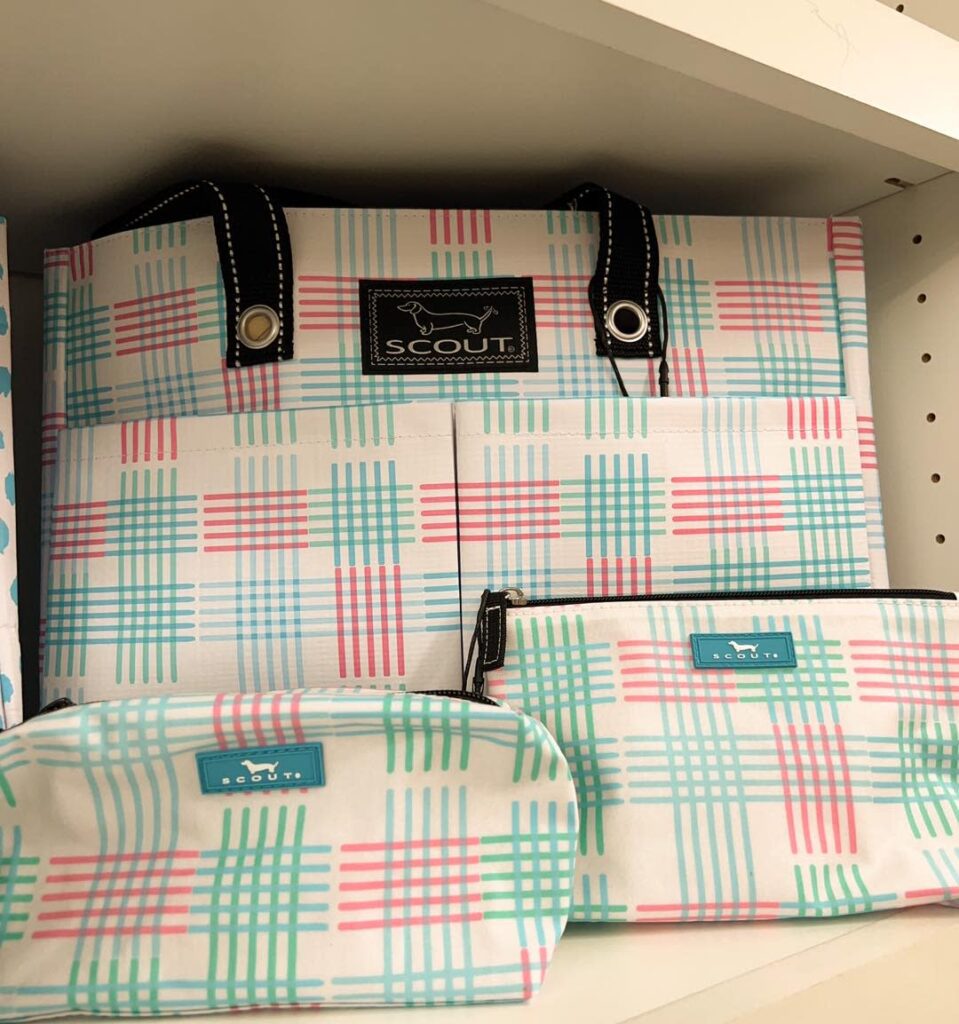 A selection of handbags and toiletry bags with a geometric print with pink, green, and blue lines