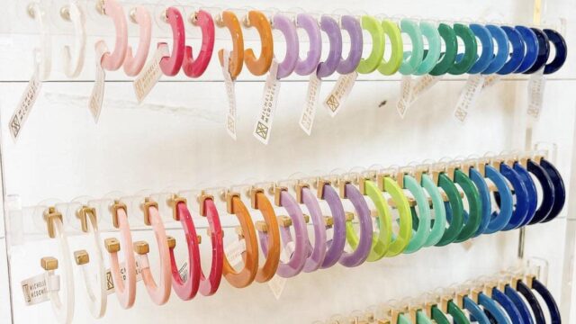 A colorful display of acrylic hoop earrings arranged in rainbow order