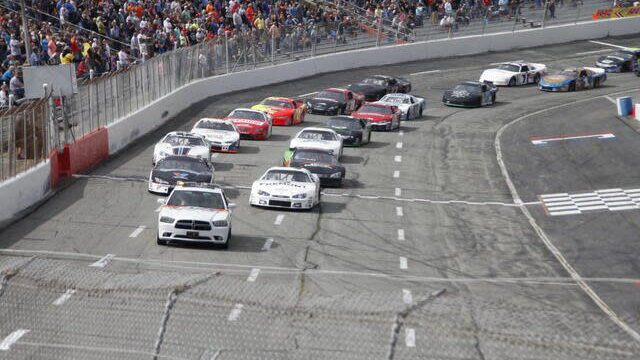 A group of motor cars cross the finish line on the racetrack