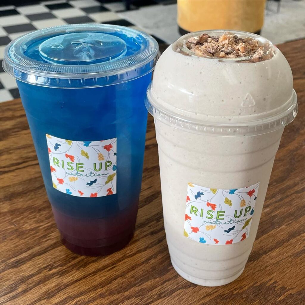 A blue iced beverage in a plastic to-go cup and a thick blended beverage in a plastic to-go cup