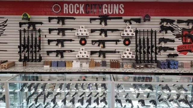 A display of guns in glass cases and on the back wall behind the counter