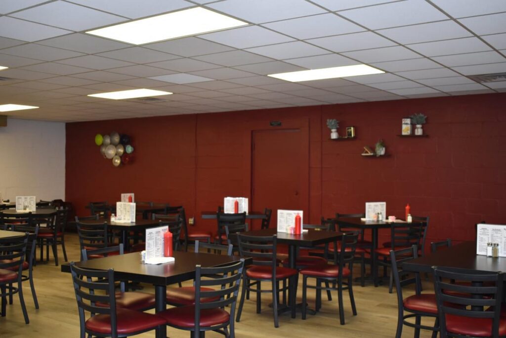 An empty restaurant with black square tables and chairs