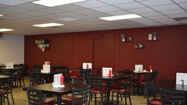 An empty restaurant with black square tables and chairs