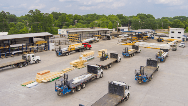 Empty flatbed trucks parked in lines, waiting to be loaded with building materials