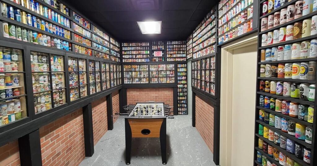 A small room with a foosball table and shelves of colorful cans lining the walls