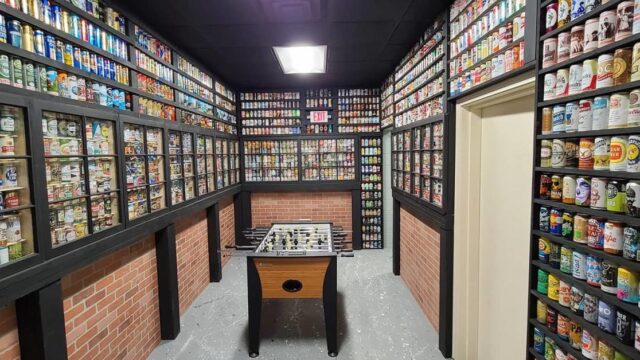 A small room with a foosball table and shelves of colorful cans lining the walls