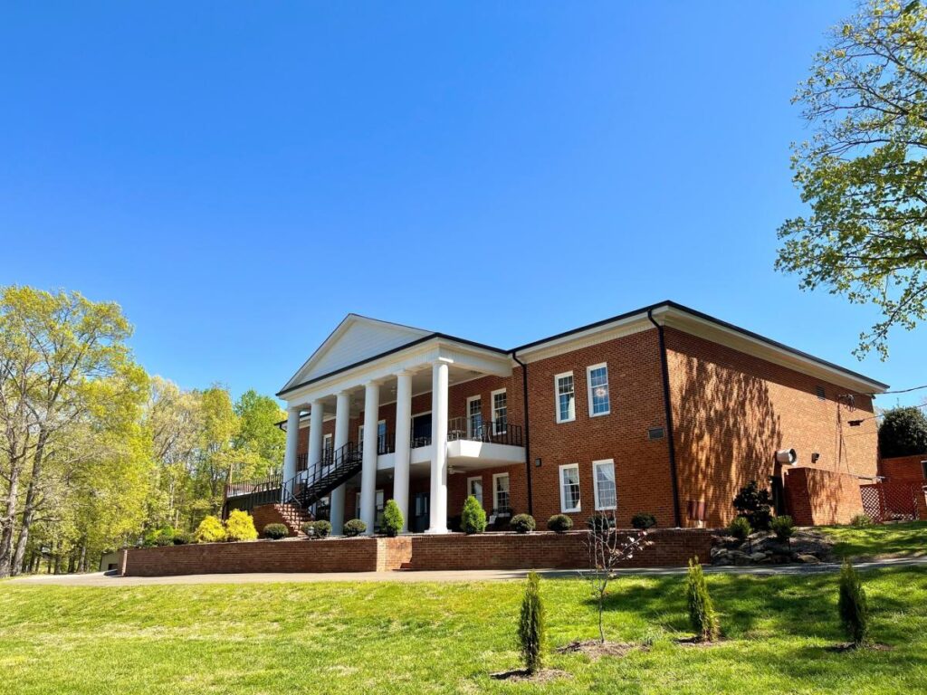 A large two-story red brick building with a white portico and large split staircase in front