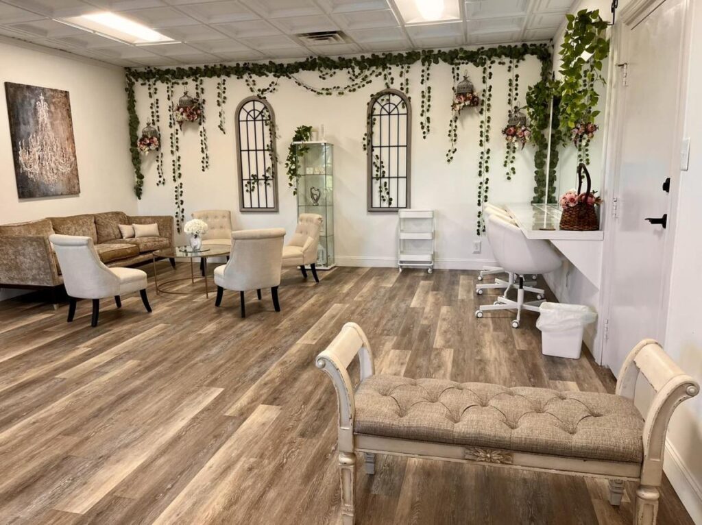 A seating area with couches and armchairs, and walls draped with greenery garlands and flowers