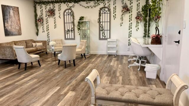 A seating area with couches and armchairs, and walls draped with greenery garlands and flowers