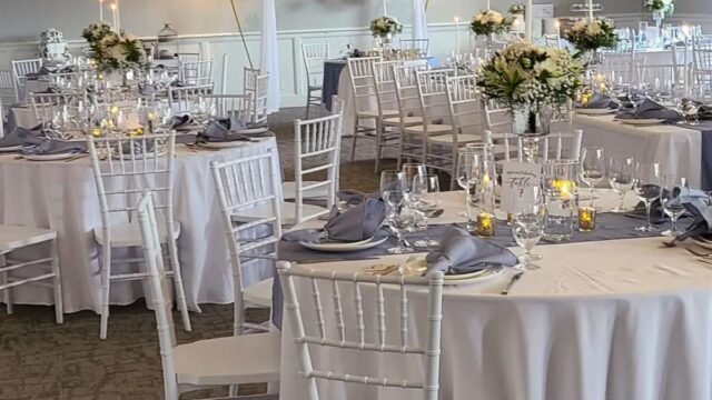 Round tables with white chairs and white tablecloths in an interior event space