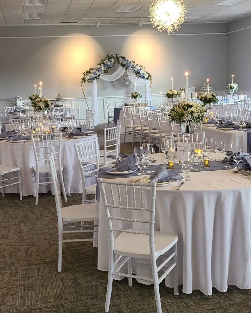 Round tables with white chairs and white tablecloths in an interior event space