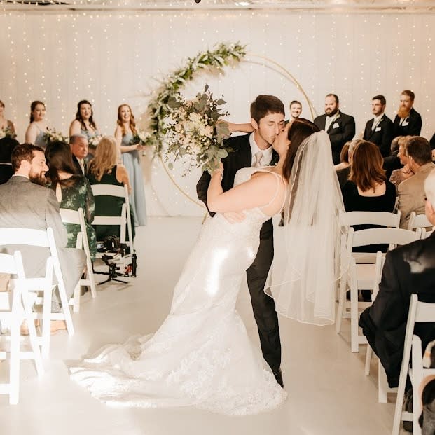 Surrounded by guests, a bride and groom kiss after the wedding ceremony