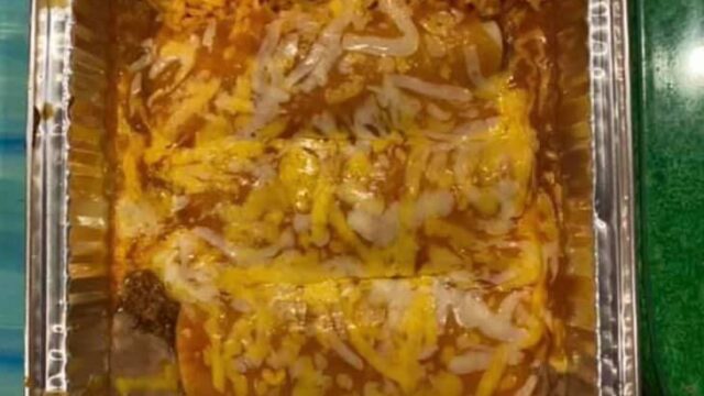 Three enchiladas topped with cheese plus a side of rice in a rectangular foil container